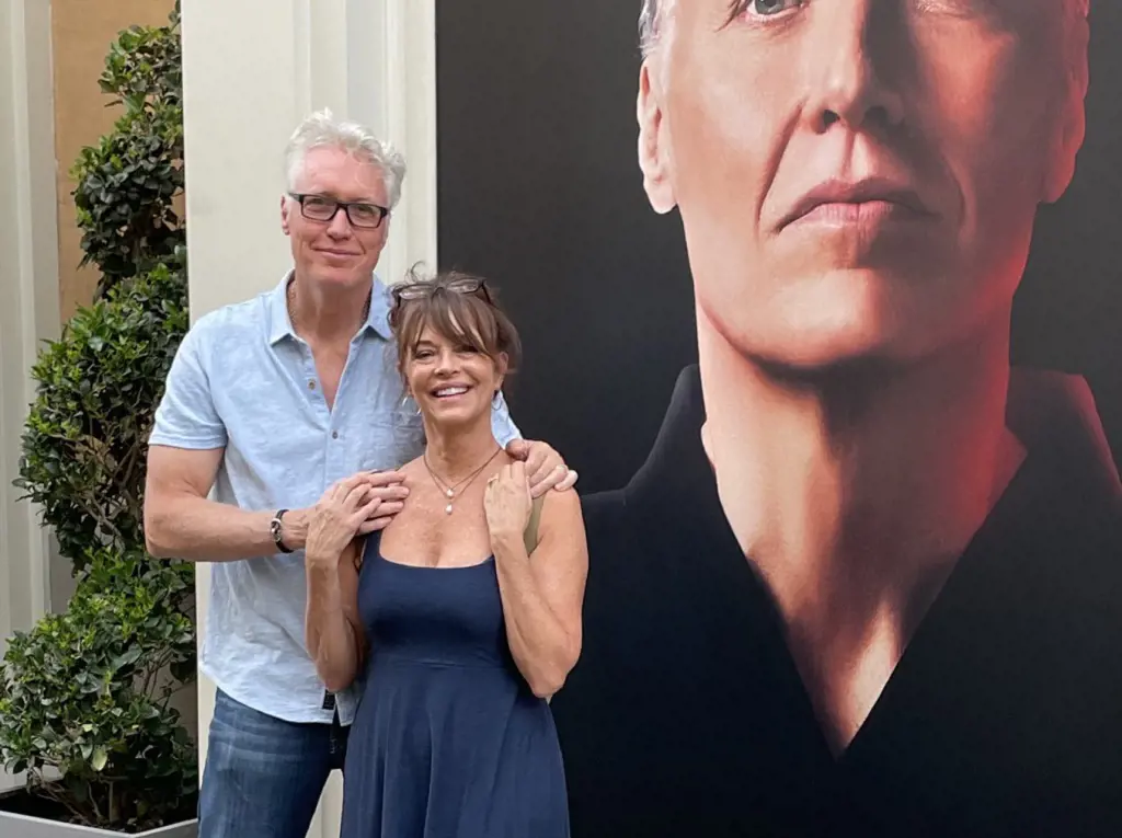 Mary Page Keller and Thomas Ian Griffith in front of the poster of Cobra Kai