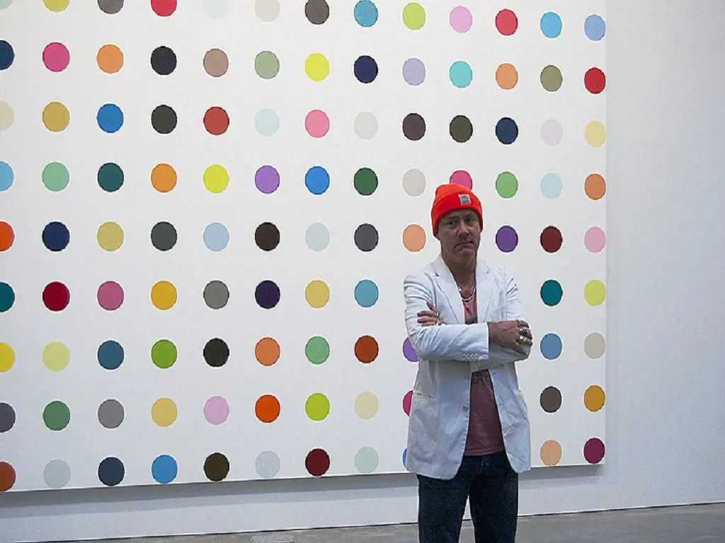 Damien Hirst in front of his art at a gallery.