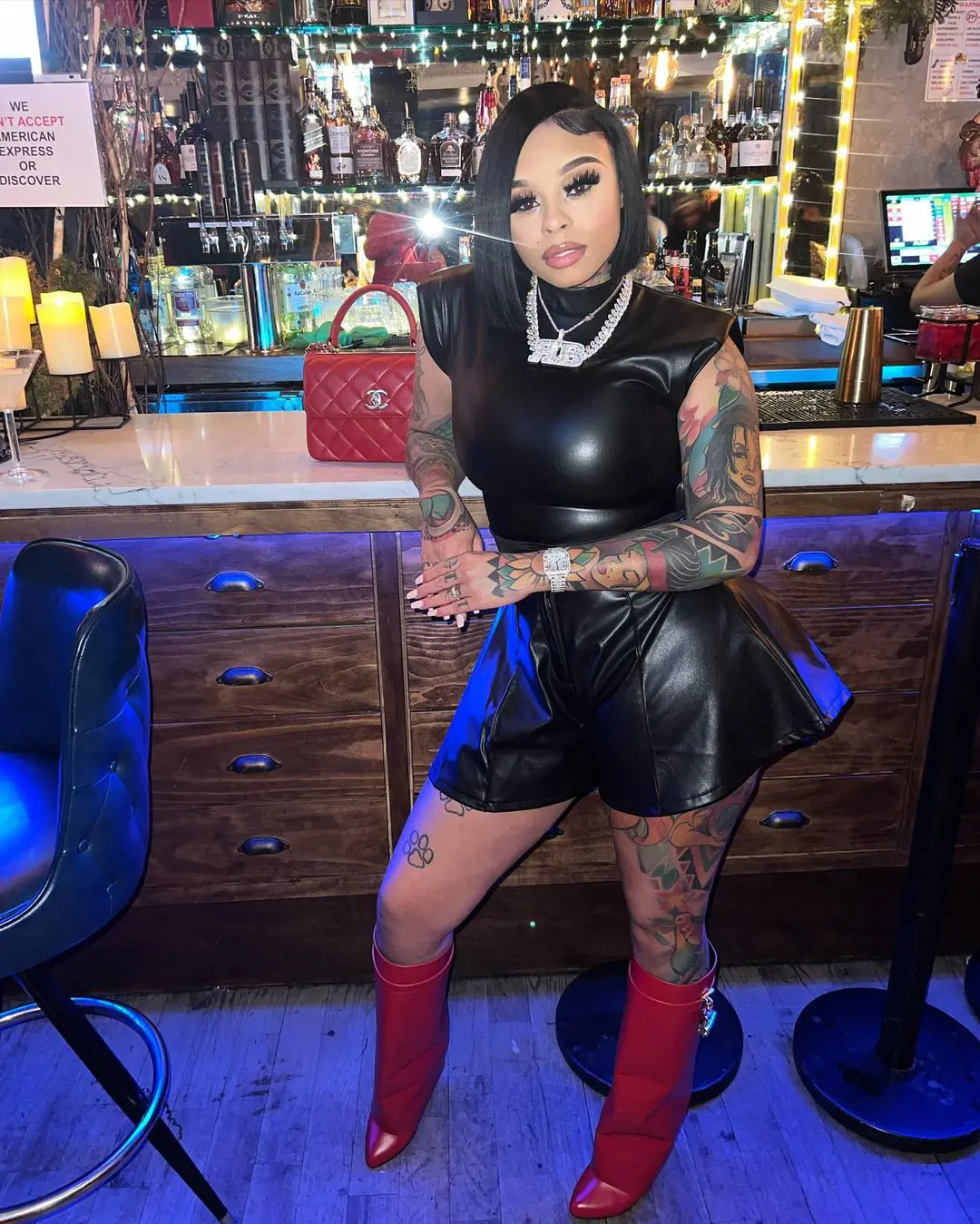 Razor in a bar in extravagant clothes, including a handbag and a Red long boot. She even wore jewelry like a ring and two necklaces. 