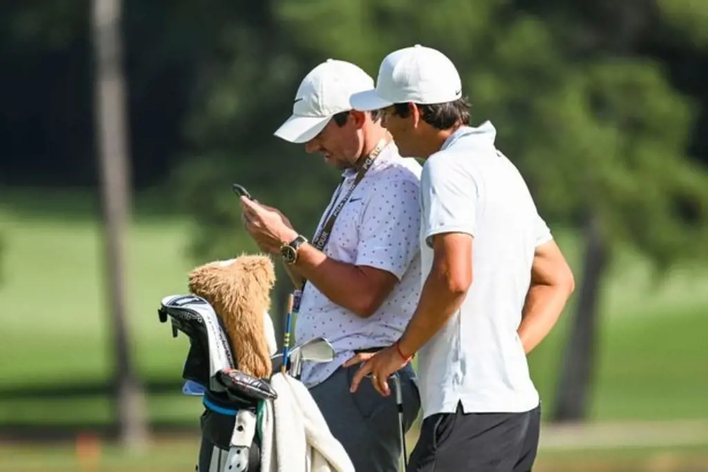 Rory and Harry shares a smile looking at the phone during practice for the TOUR Championship
