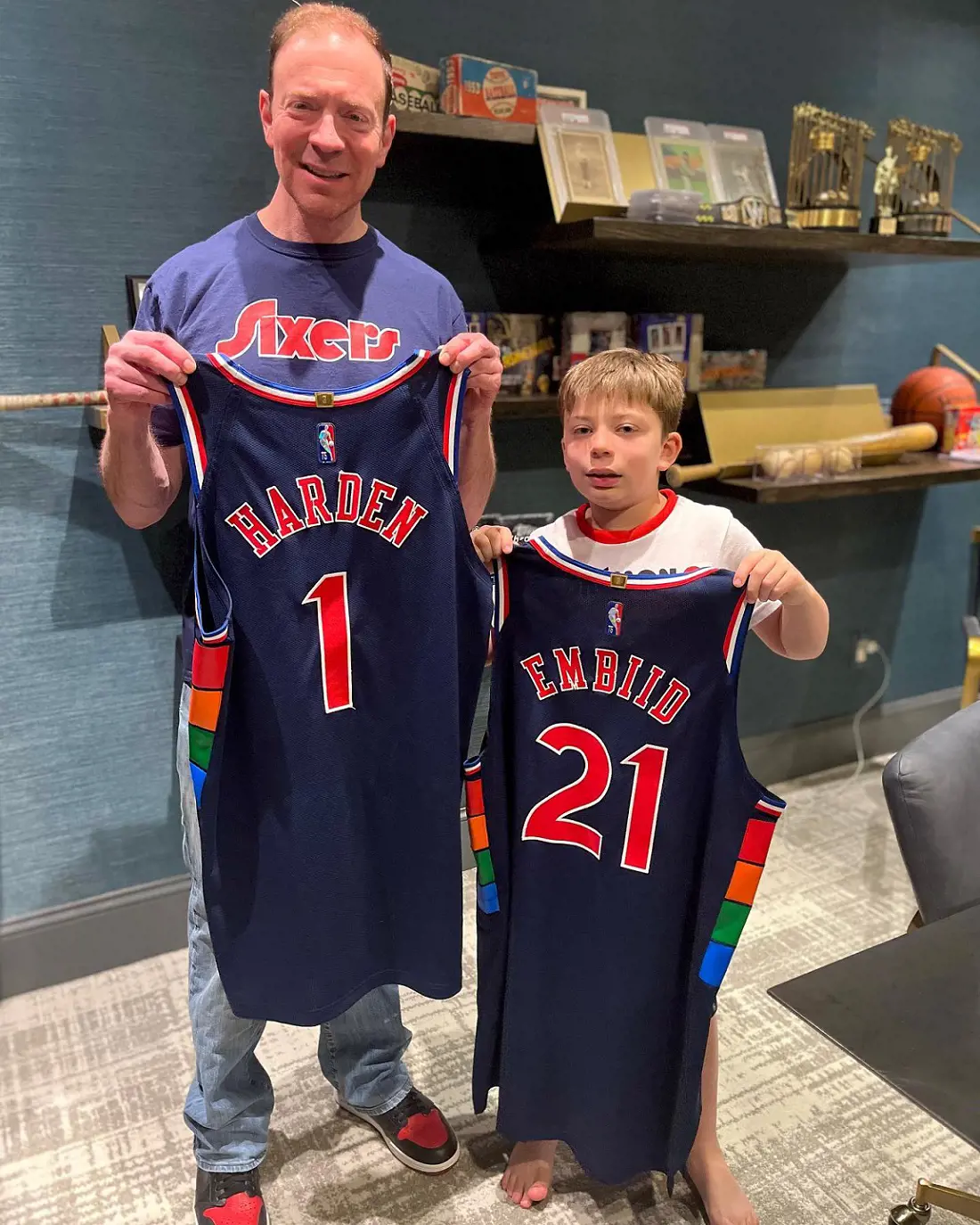 Ken along with his son Paul holding Sixers game used uniform of Harden and Embiid. 